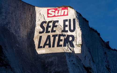 The image depicts a video projection onto a cliff face at Dover, which reads "The Sun. SEE EU LATER"