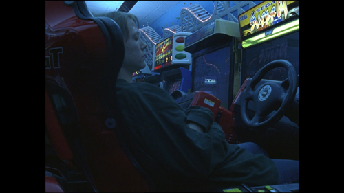 This image depicts a young woman sleeping in an amusement arcade.