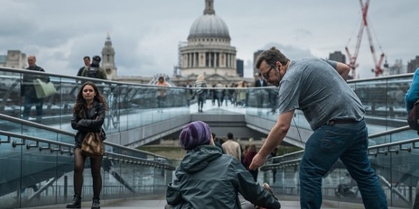 A homeless person receiving spare change in London - St Paul's Cathedral is in the background