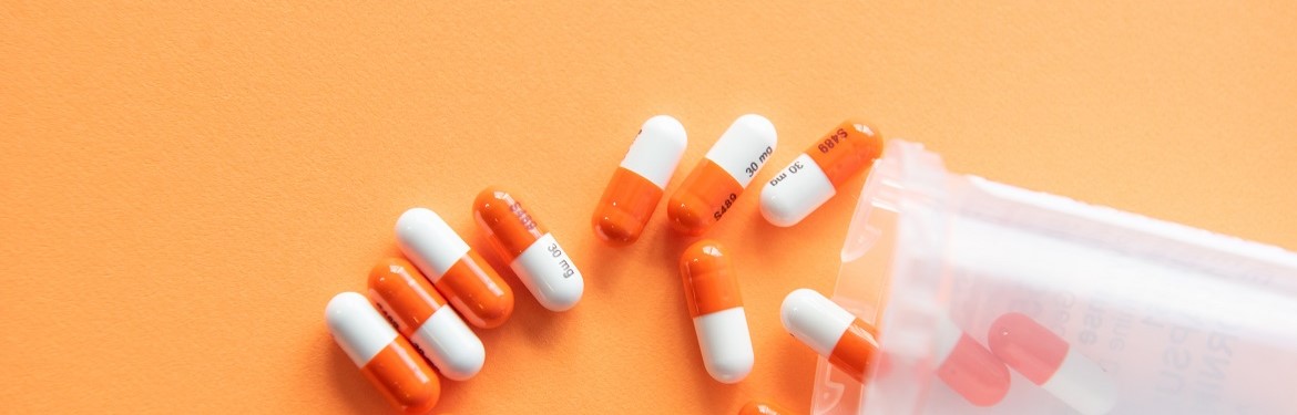 Prescription drugs on an orange background with a pill bottle. Orange pills.