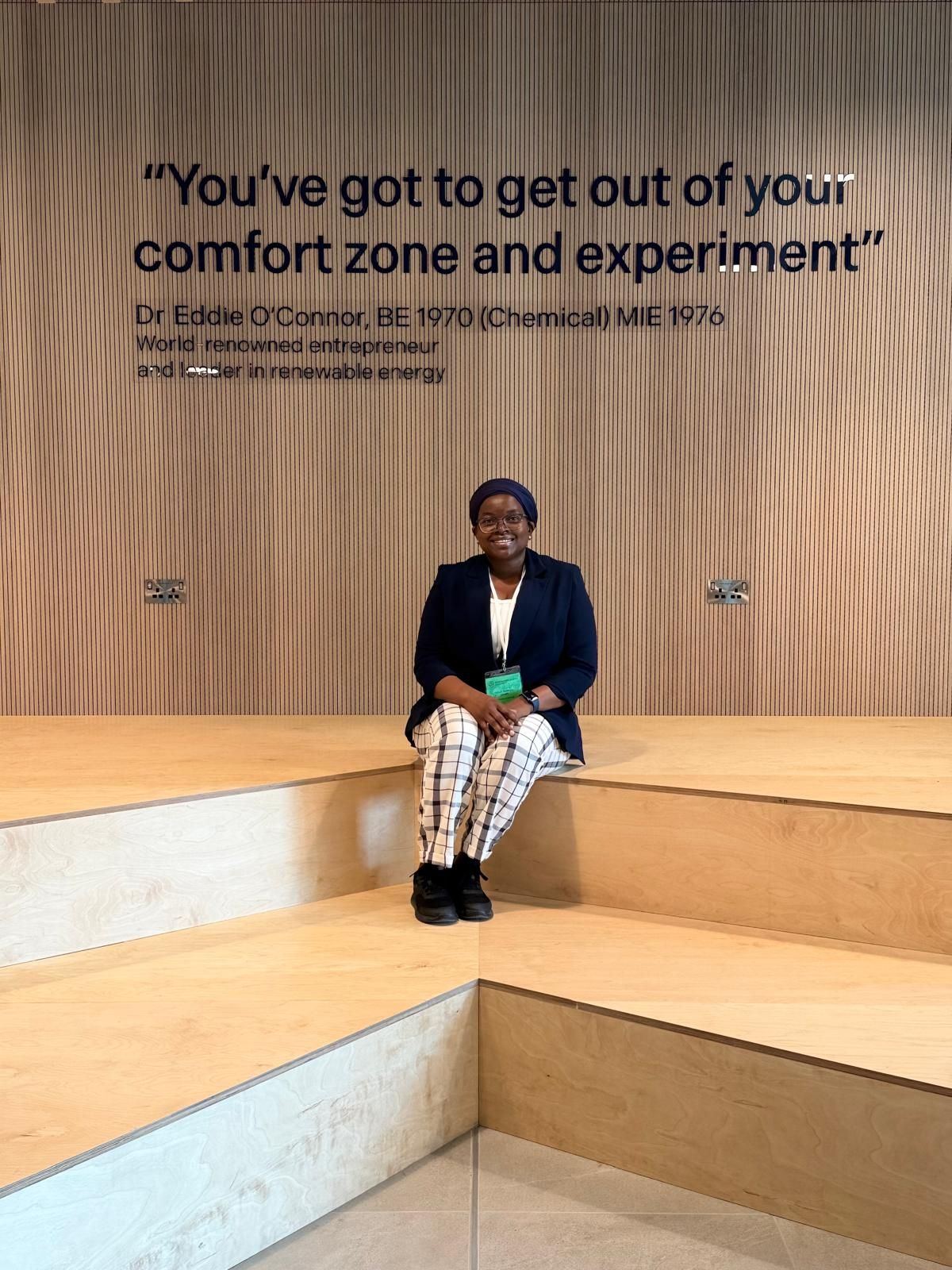 Hadijah sits on steps and smiles directly at camera