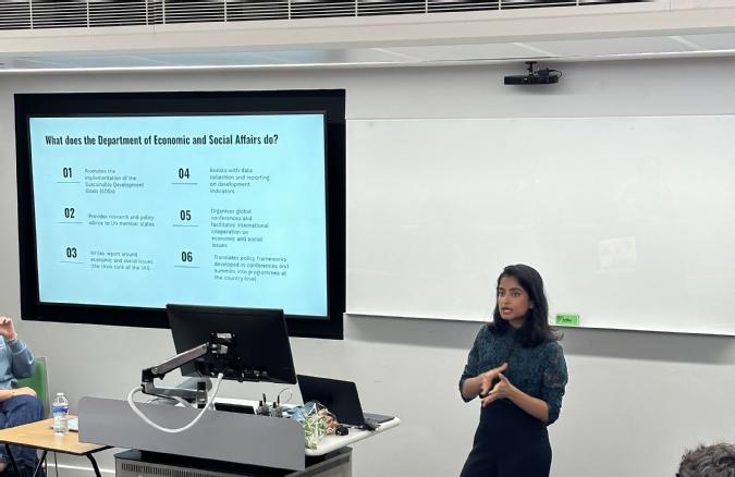 Maria standing in front of powerpoint presenting to audience