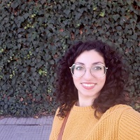 Hala, wearing a yellow top, smiling at the camera