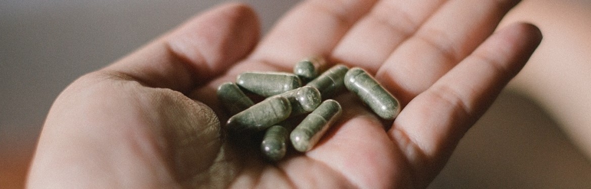 A person holding green pills in their hand
