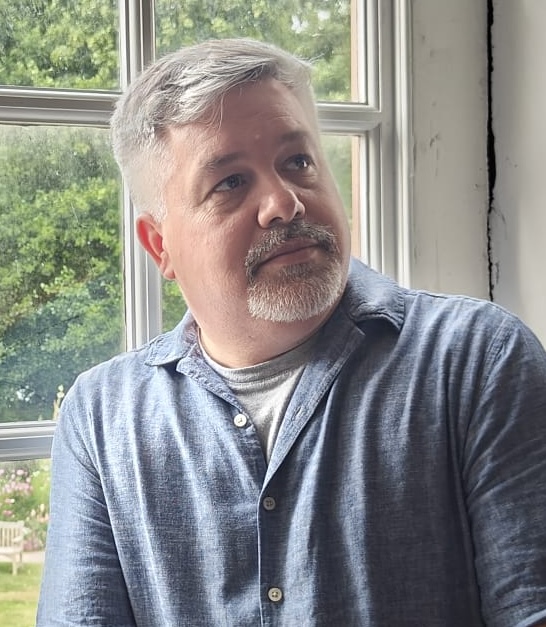William Rupp sits in front of window looking away from camera
