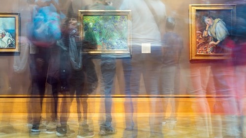 Blurred outlines of people looking at artwork in a gallery