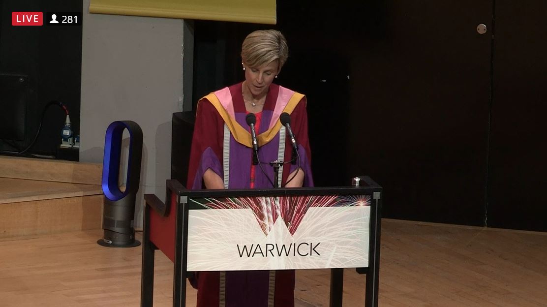 Stephanie standing at a podium reading a speech about the WAPTE winners at the 2022 Graduation Ceremony