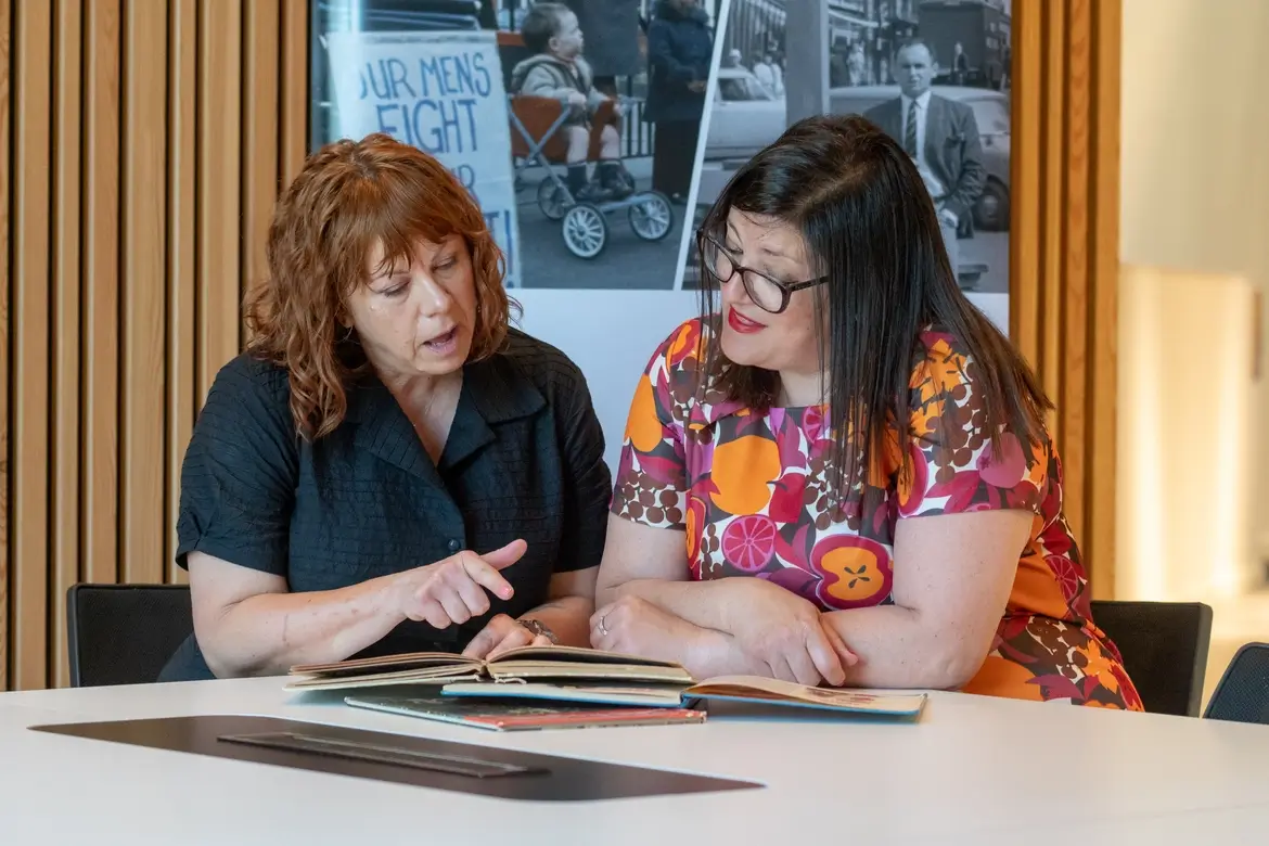 Two people having a discussion over a book