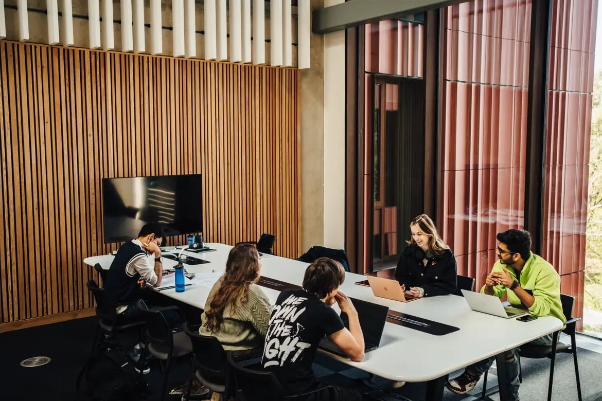 Five University of Warwick students working collaboratively at a desk indoors