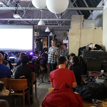 Image of a person speaking in front of a screen