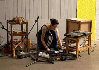 A woman plugging a violin into a record desk 