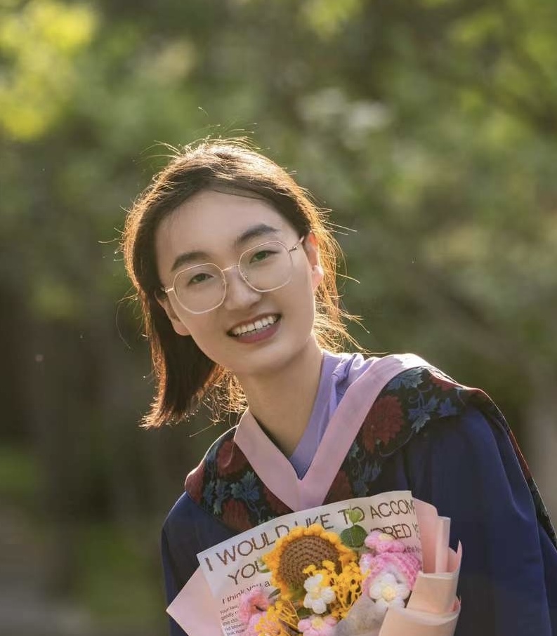 Sutong Duan, a woman with black hair, wearing glasses and smiling at the camera
