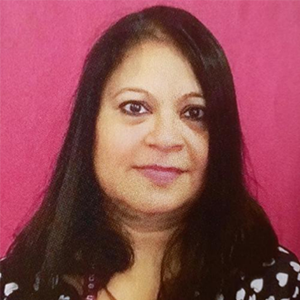Upama Ghosh a woman with shoulder length black hair smiling at the camera.