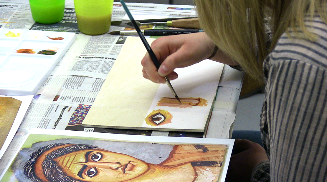 Participant painting details of a mummy portrait with tempera (egg-based) pigment