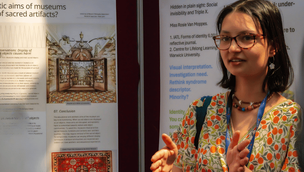 Student in apricot and green dress discussing her research