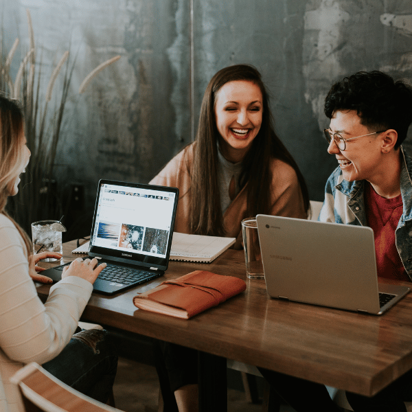 Three students with laptops laughing