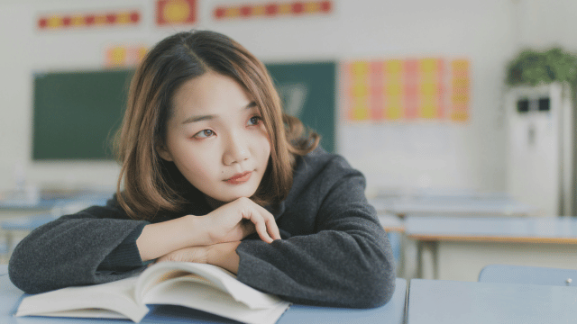 Girl with book staring off into the distance