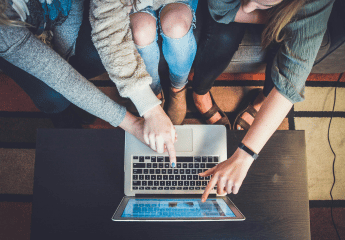 three people looking at a laptop