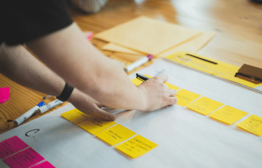 Hands of person adding post it notes to board