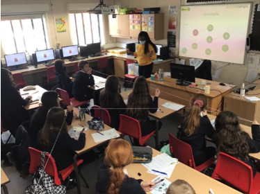 An image of a classroom with students interacting with a string as a metaphor for disease spread