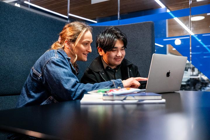 Image of two PGRs reading from a laptop