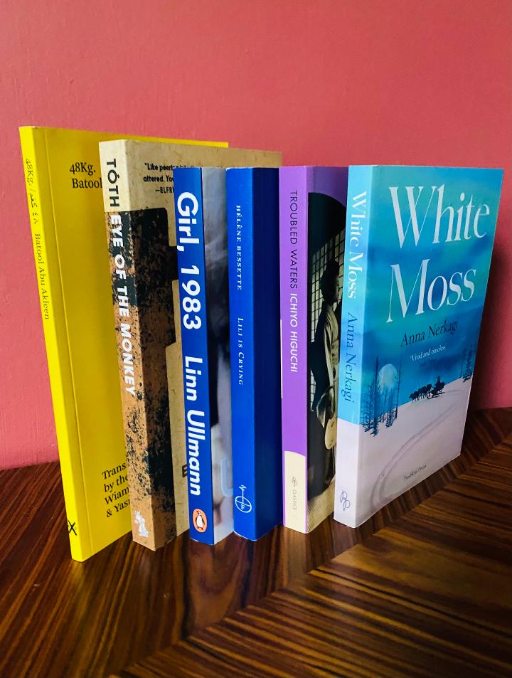 The six titles shortlisted for the Warwick Prize for Women in Translation are photographed stood on a table with their spines facing the camera. 