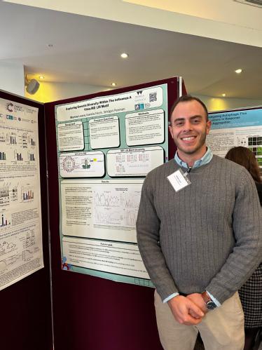 Image shows a man standing beside a poster at a scientific conference