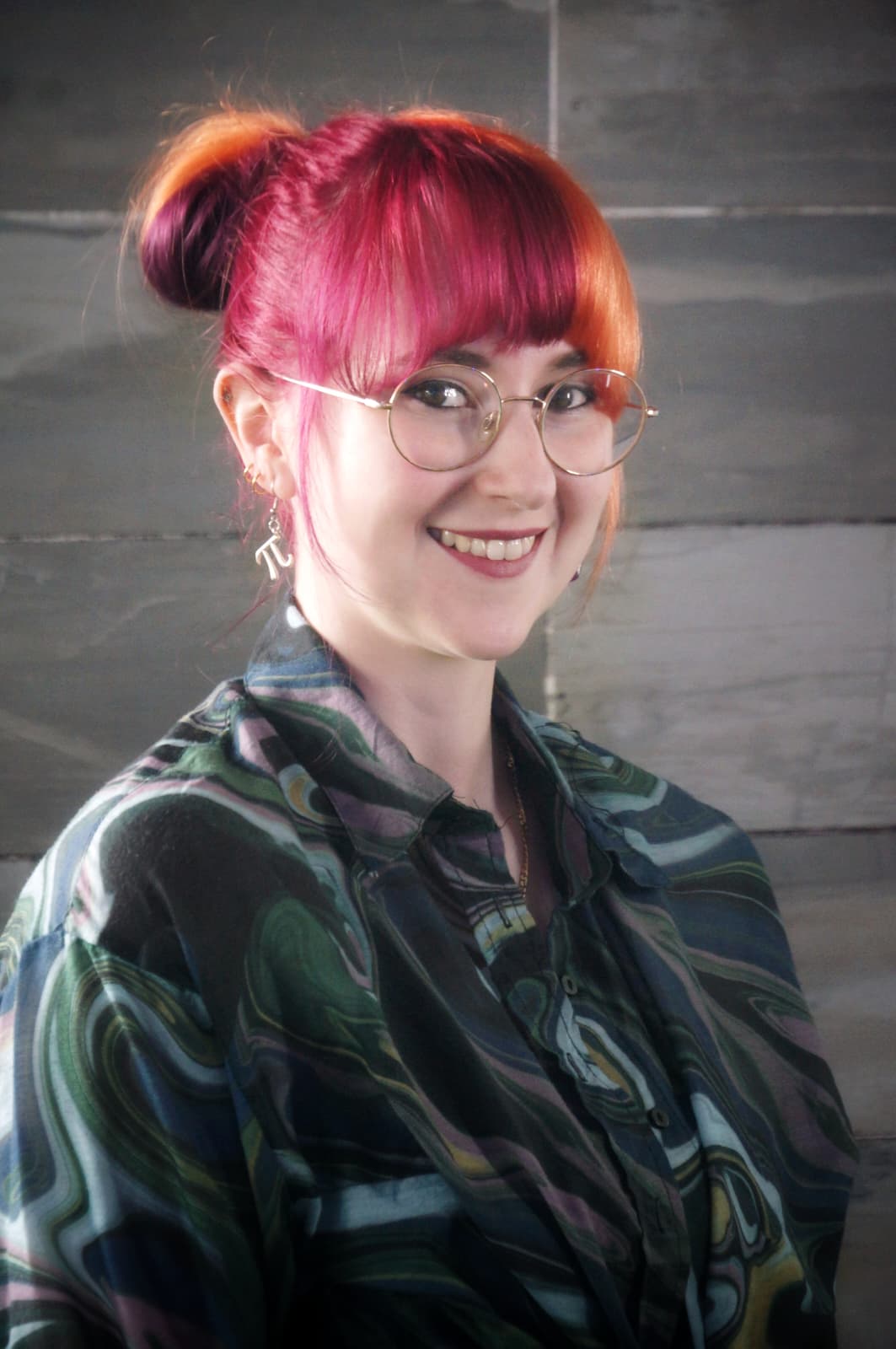 headshot of kat, a 20-something woman with split purple/orange hair wearing glasses