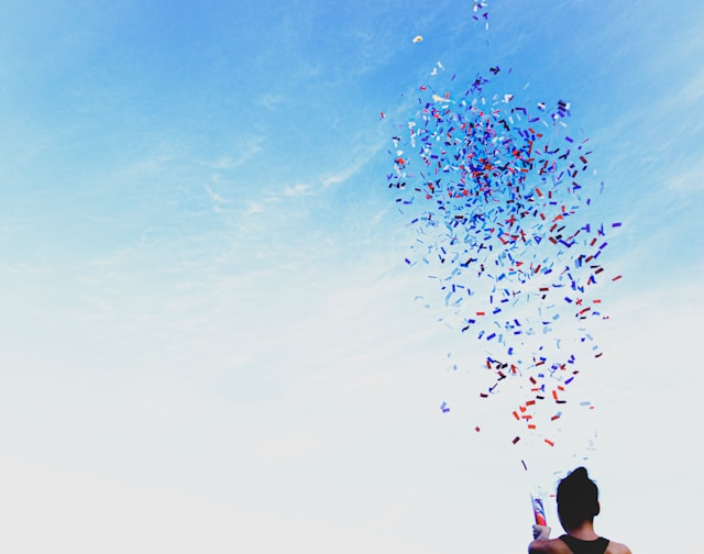 A women fires confetti into the blue sky
