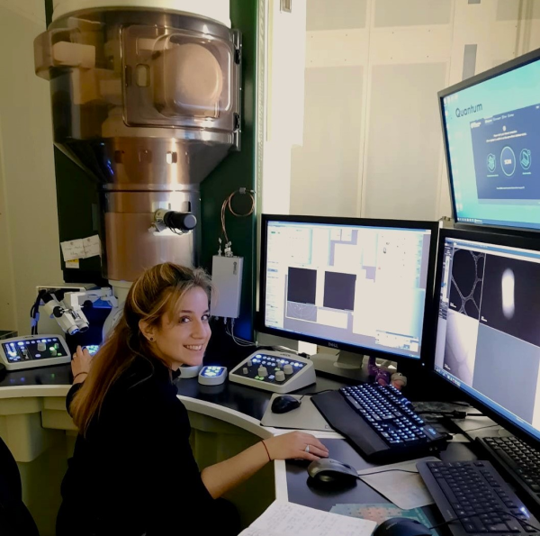 Woman at computer in front of a electron microscope