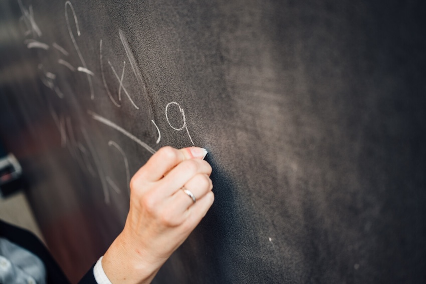 A member of the Department of Computer Science writing mathematics on a board.