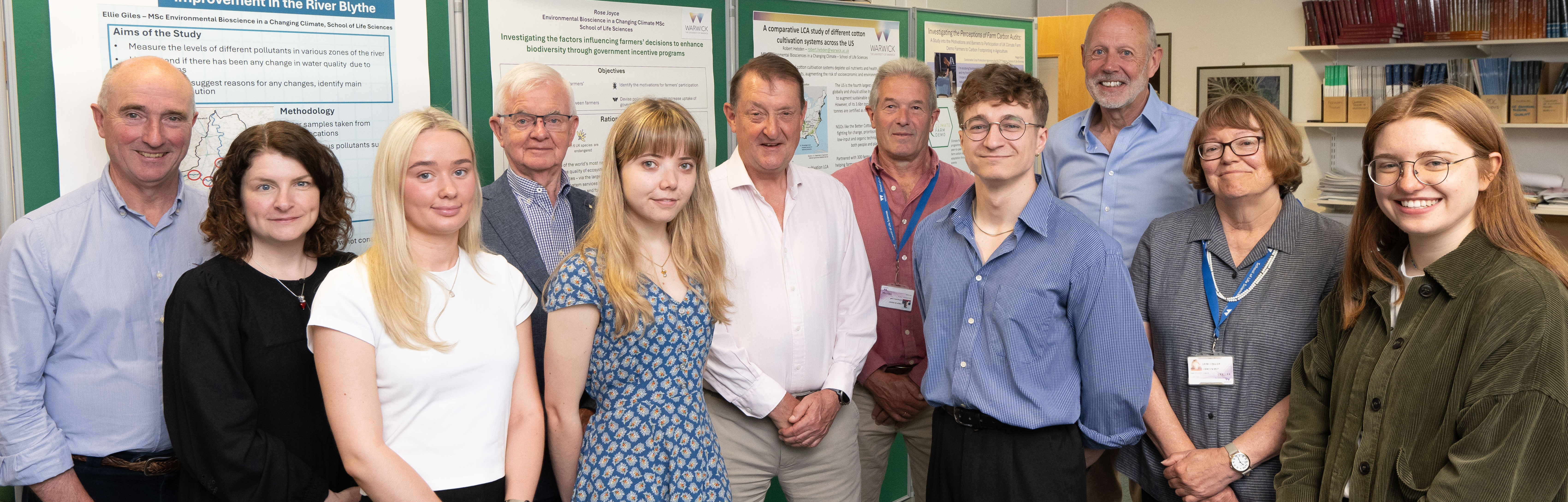 Group of Trustees, students and academics in front of poster display