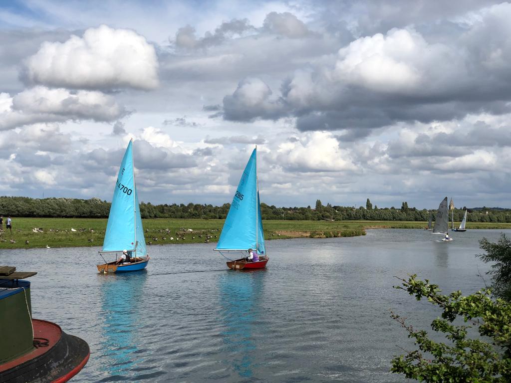 Two blue sailing dinghies on a river on a cloudy day