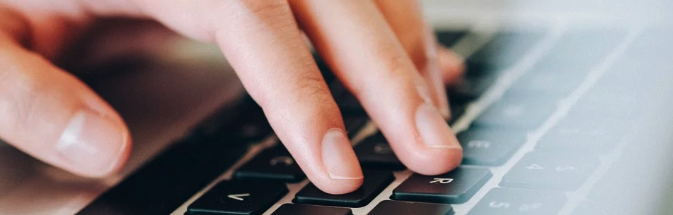 Hand typing on a laptop