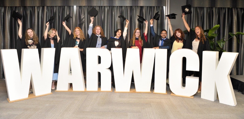MBio Students at graduation throwing hats up