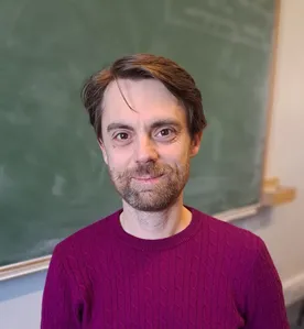 Tim Austin sitting in office in front of blackboard