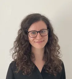 Ellen is a young white woman with dark curly hair and glasses