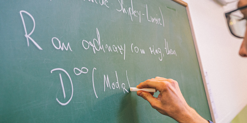 A close up of someone drawing mathematical equations on a chalk board