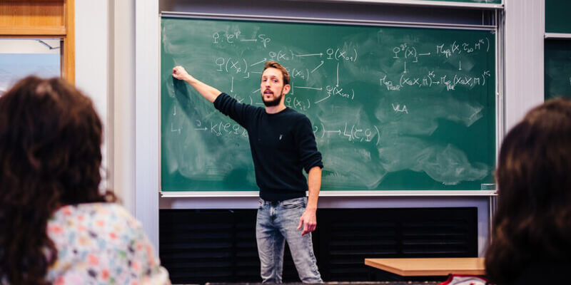 A lecturer teaching in front of a chalk board