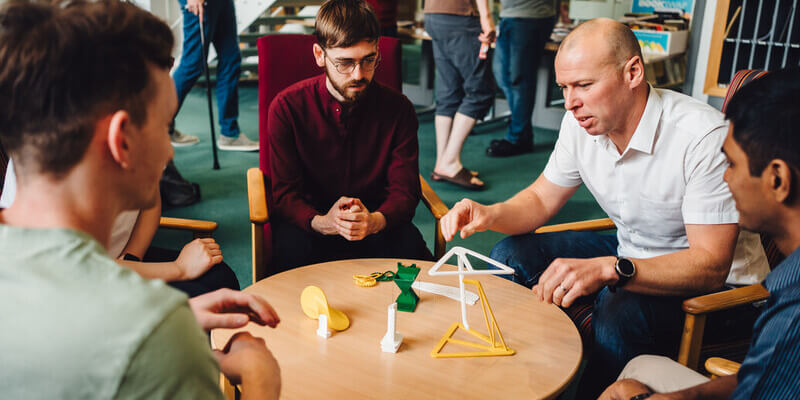 Staff and students sitting around a low table examining some mathematical models