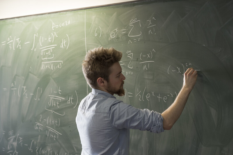 PG Maths student writing maths formula on a blackboard