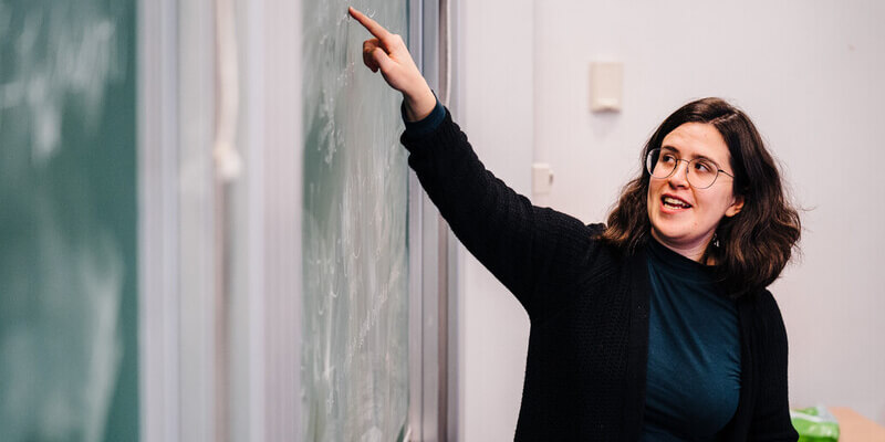 A lecturer pointing at a board