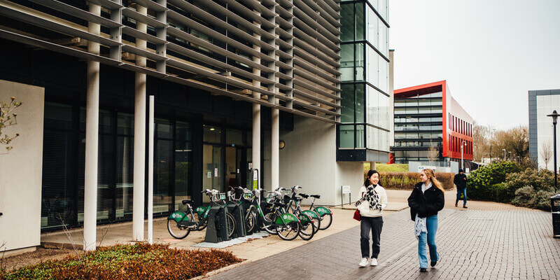 Two students walking and talking outside a university building