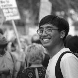 Black and white picture of Jacques Bara, an Asian male, in front of a demonstration.