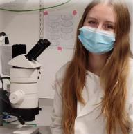 photo of PhD student Deannah wearing a face mask and working in the lab