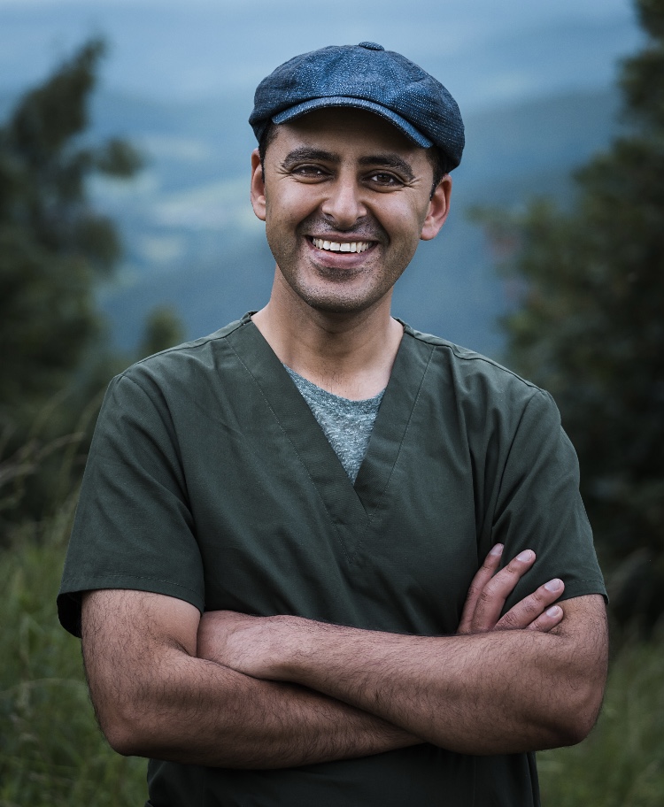 Dr Shahed Yousef smiling to camera, trees and hills in the background