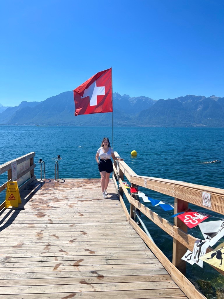 Female student beside lake with swiss flag