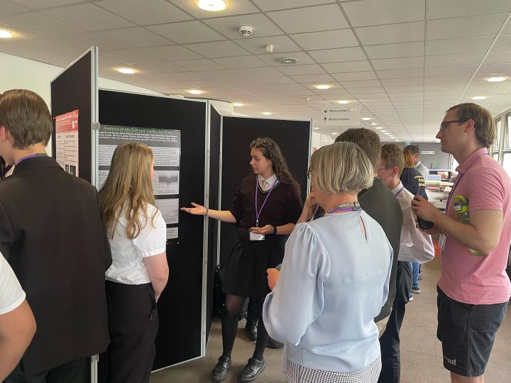 Image shows students and researchers looking at poster presentations on the concourse.