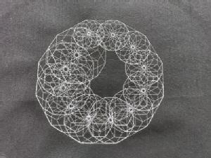 black canvas with white embroidered pattern  of circles of increasing diameter, arranged in a large circle