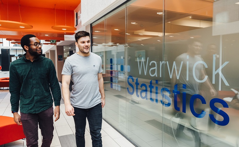 Two students walk through the atrium of the Mathematical Sciences Building.